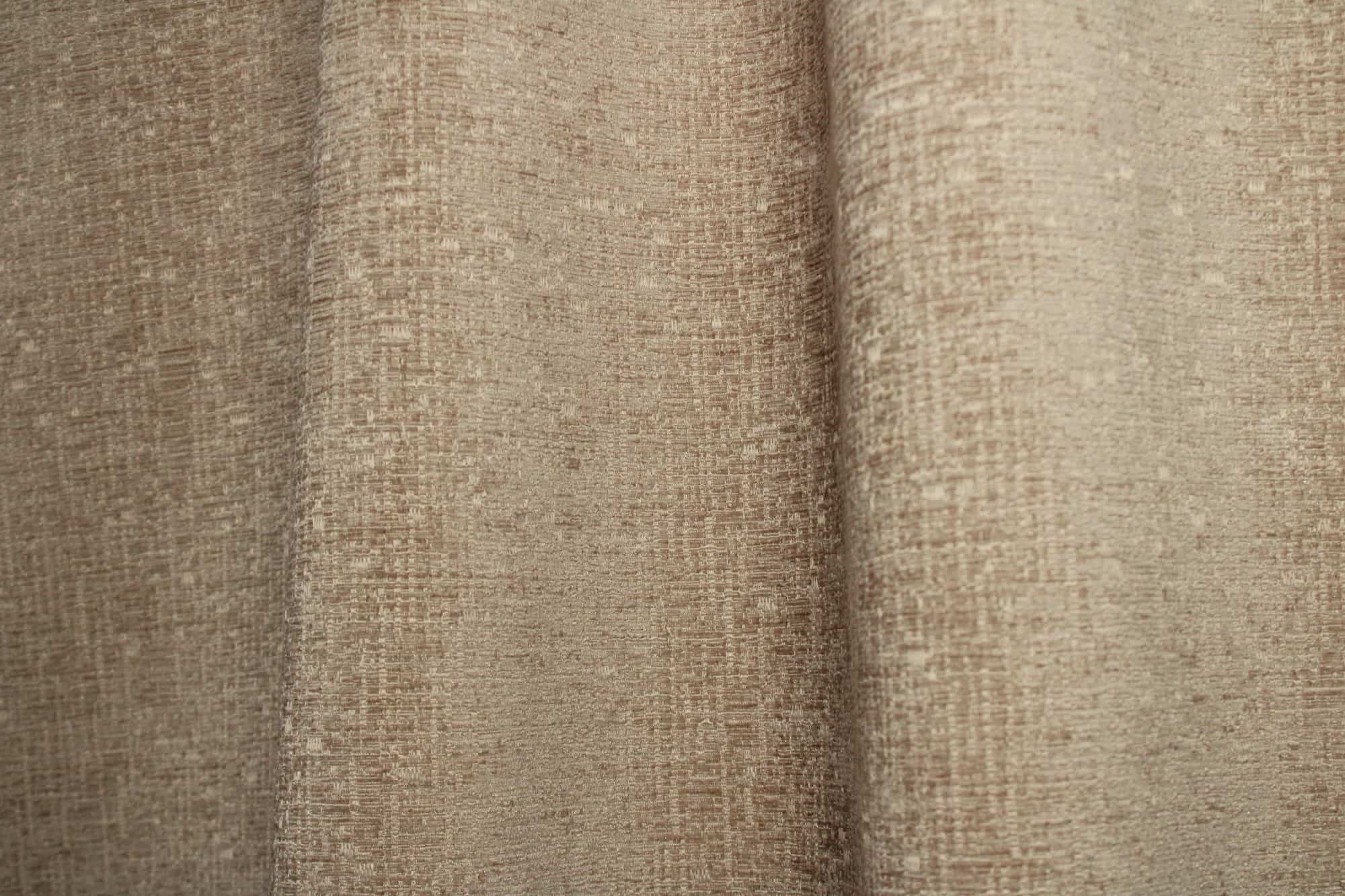 Sfeerfoto van zandkleurige teddy chenille gordijnen van Okika, getoond in de plooi, met een rustige en warme uitstraling bij natuurlijk licht in het interieur.