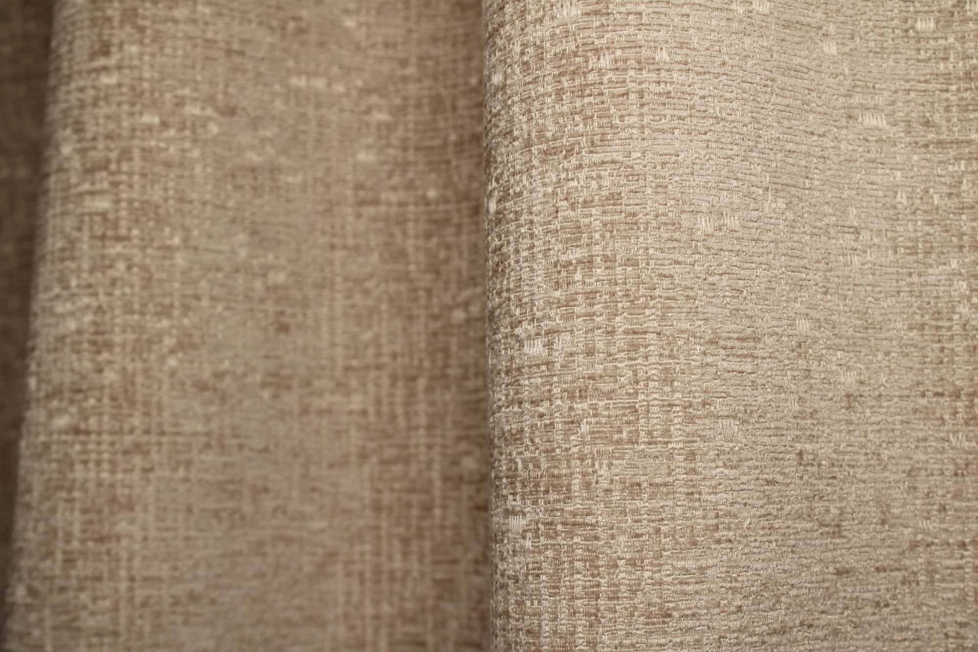 Stofdetails van zandkleurige teddy chenille gordijnen van Okika, met een volle, zachte teddy structuur en gelijkmatige chenille weving zichtbaar bij daglicht.