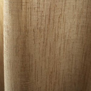 Lichtdoorlatendheid van beige linnenlook gordijnen, waarbij het daglicht zacht door de stof wordt gefilterd en de ruimte een warme uitstraling krijgt.