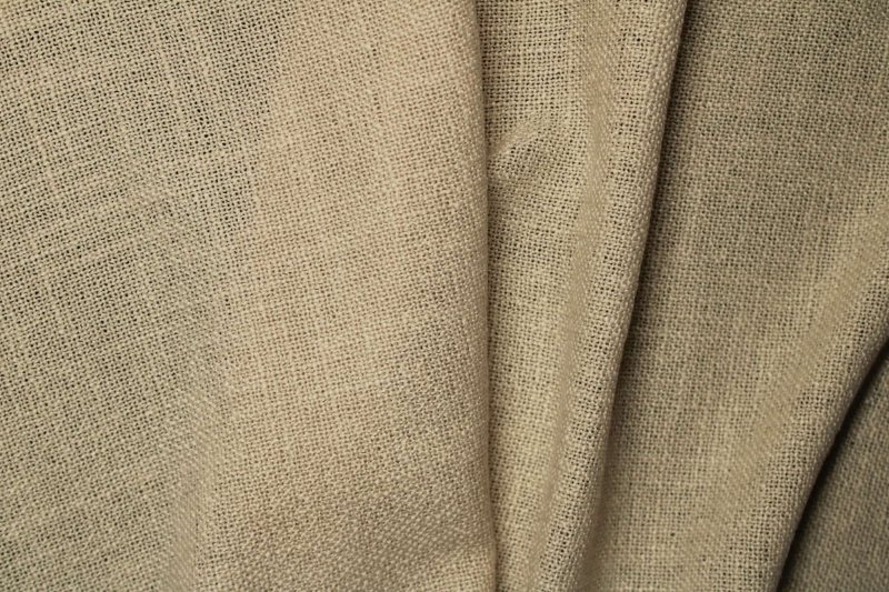 Beige vouwgordijnen uit de Boucloir collectie, gemaakt van een bouclé achtige stof met structuur, getoond als sfeerfoto