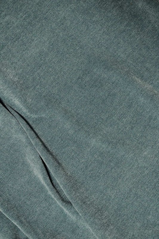 Blauwe vouwgordijnen van chenille, weergegeven als sfeerfoto met geplooide stof en een rustige, verzorgde uitstraling