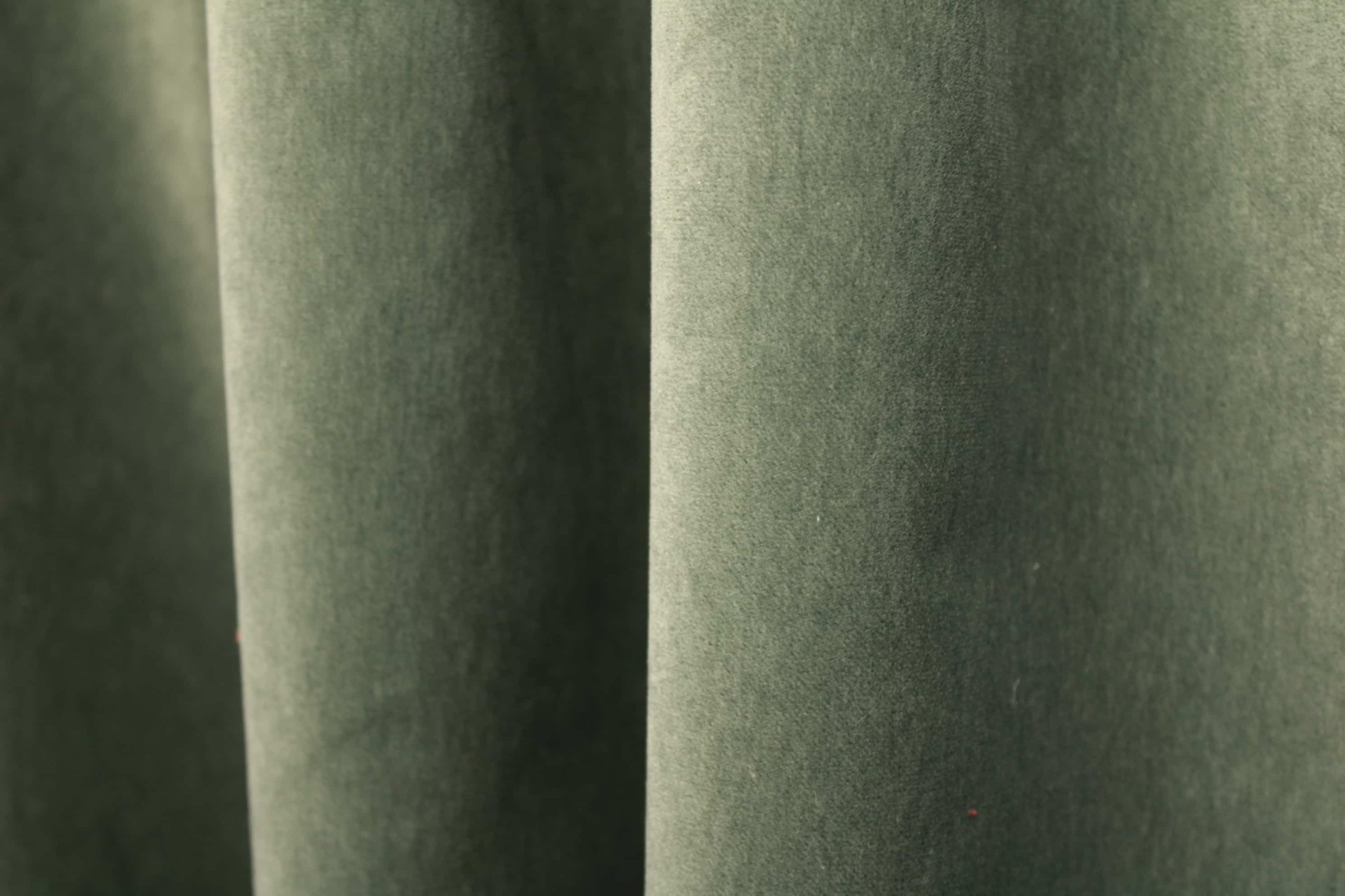 De groengrijze velours SYM2681 uit de Noble collectie, sfeerfoto waarbij de stof hangt in plooien