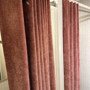 Volledig beeld van chenille velvet mauve gordijnen op ringen bij een klant in zijn pashokjes, inpritiee foto met zichtbare roede en ringen.