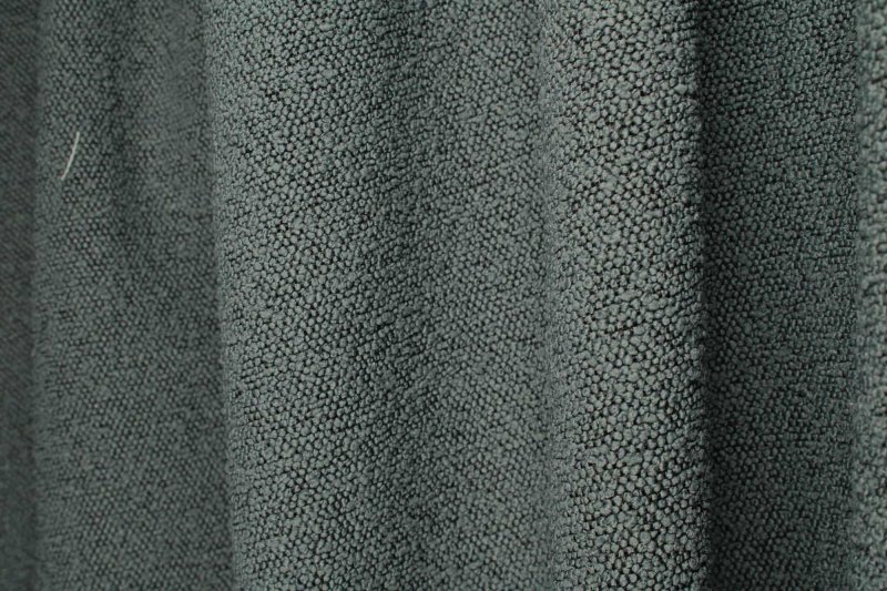 Donkerblauwe bouclé gordijnen met bolletjes structuur op een stijlvolle interieur sfeerfoto met plooi