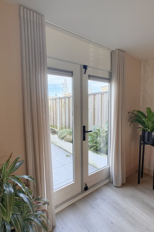 Close-up van Norena wavegordijnen in offwhite in de woonkamer, met zachte en gelijkmatige plooien zichtbaar