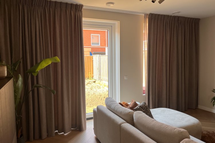 Imperial zacht taupe overgordijnen in dubbele plooi in een moderne woonkamer bij de klant thuis