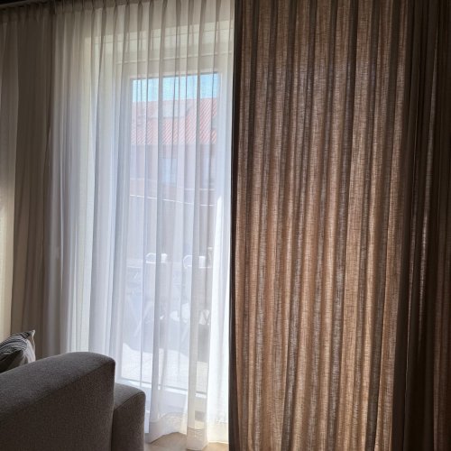 linnen look gordijnen in dubbele plooi half open bij een klant thuis met subtiele structuur en zachte lichtinva