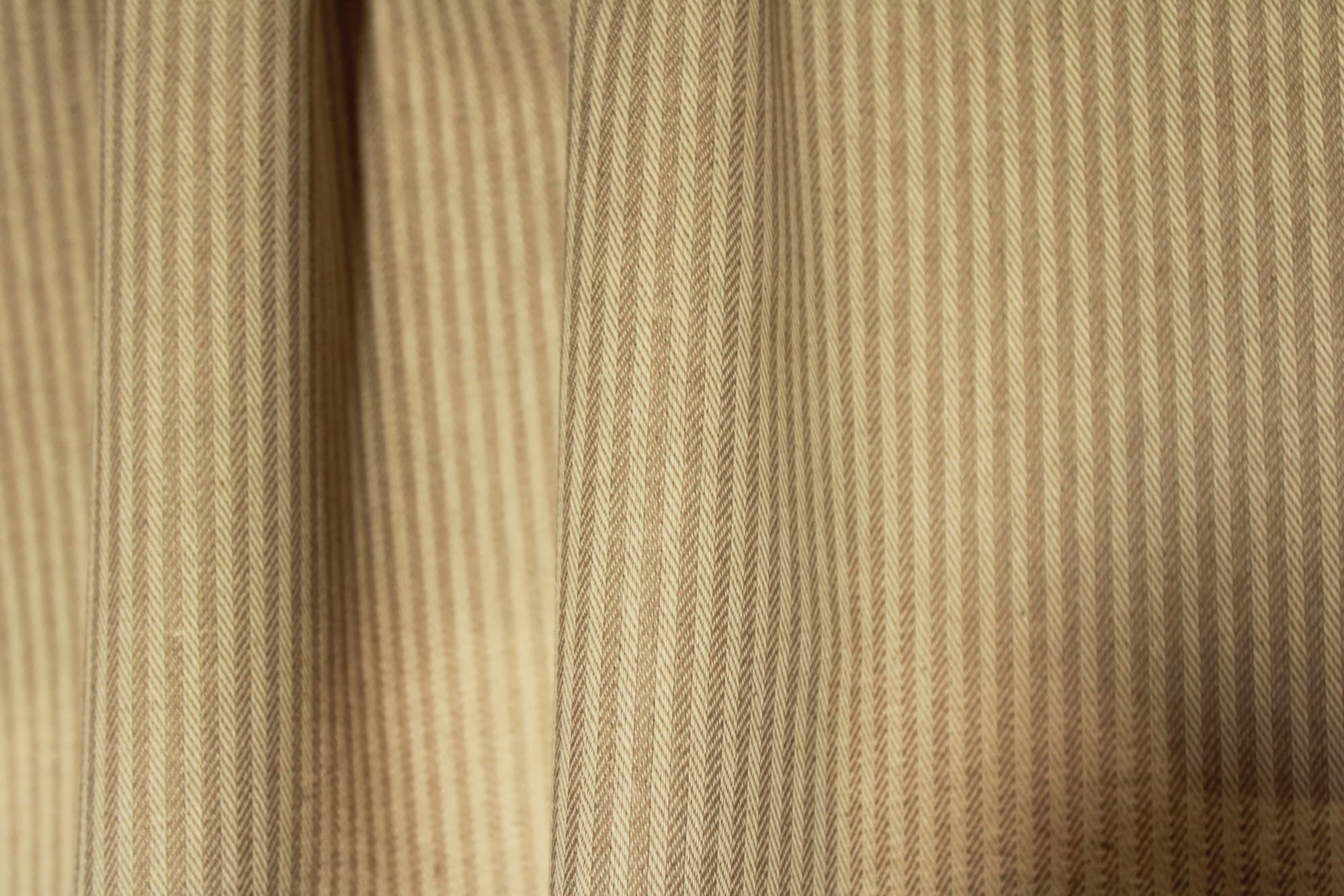 Sfeerfoto van beige gordijnen in de plooi met strepen en subtiel visgraatpatroon qual 2604