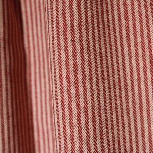 Detailfoto van burgundy gordijnstof met ingeweven strepen en visgraatstructuur