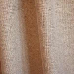 Sfeerfoto van beige verduisterende PureShade gordijnen. De stof hangt in gelijkmatige plooien en laat de subtiele structuur goed zien.