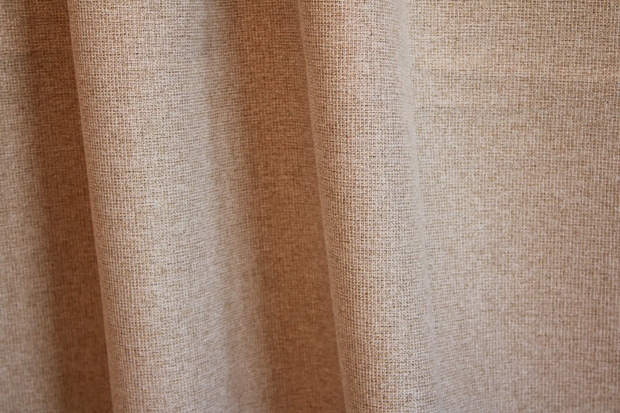Sfeerfoto van beige verduisterende PureShade gordijnen. De stof hangt in gelijkmatige plooien en laat de subtiele structuur goed zien.