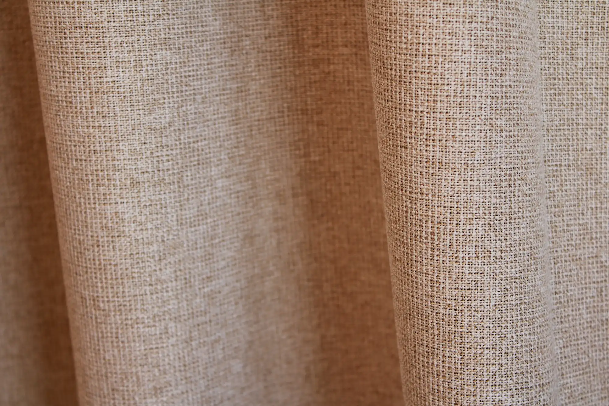 Stofdetail van beige Pureshade verduisterende gordijnen met zicht op de voorzijde en de stof heeft een meekleurende verduisterende achterkant.