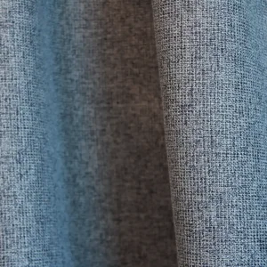 Sfeerfoto van blauwe verduisterende PureShade gordijnen in een interieur. De diepe blauwe kleur en de subtiele geweven structuur van de stof zijn goed zichtbaar.