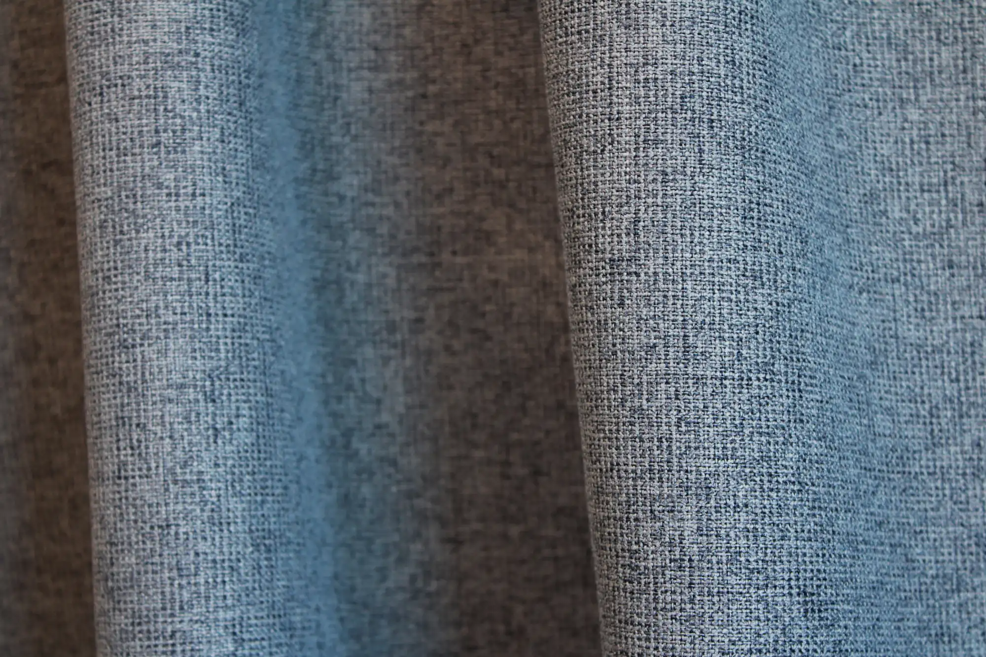 Sfeerfoto van blauwe verduisterende PureShade gordijnen in een interieur. De diepe blauwe kleur en de subtiele geweven structuur van de stof zijn goed zichtbaar.