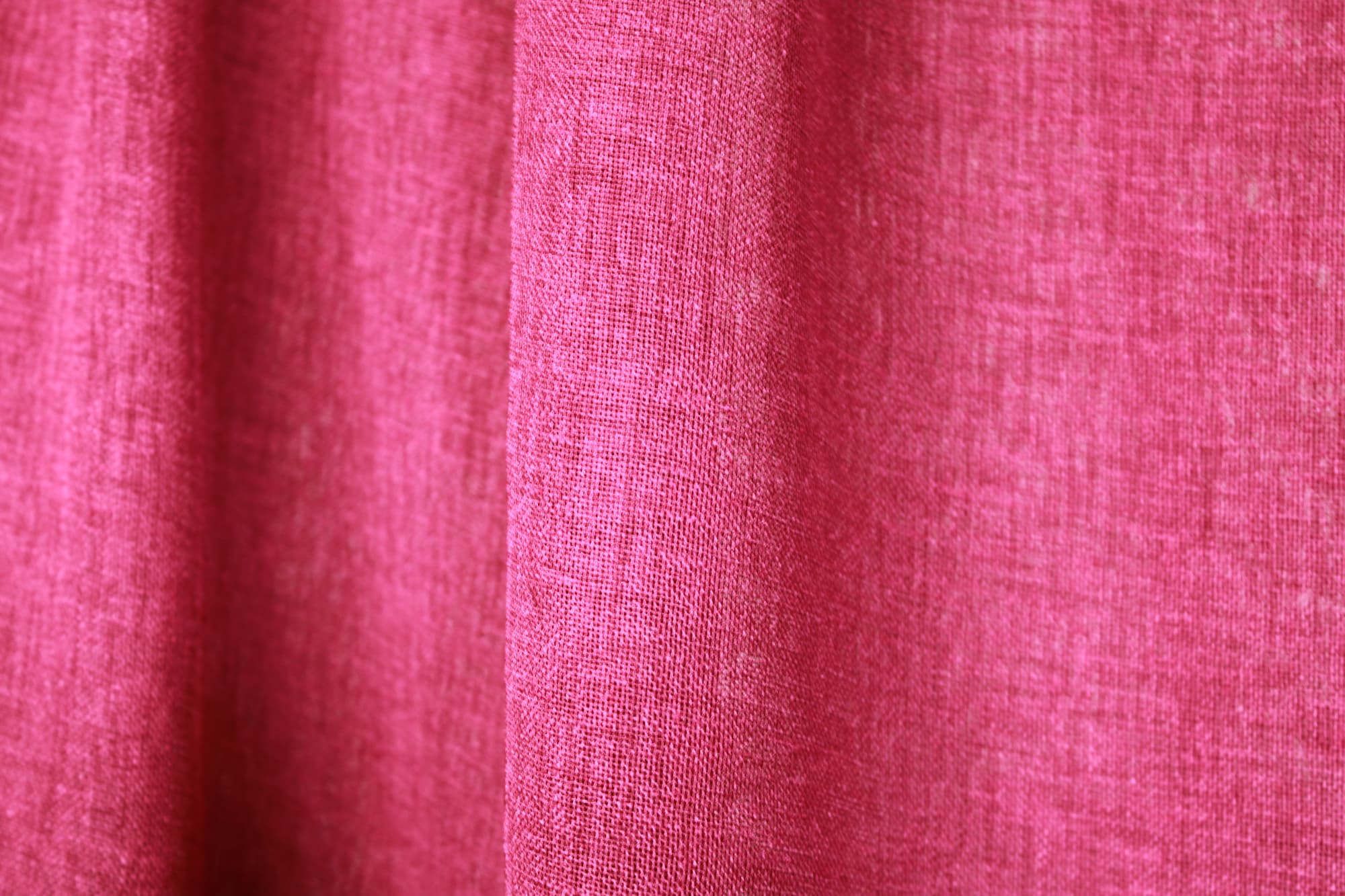 Stofdetail van donker roze vitrage met een linnenlook weving