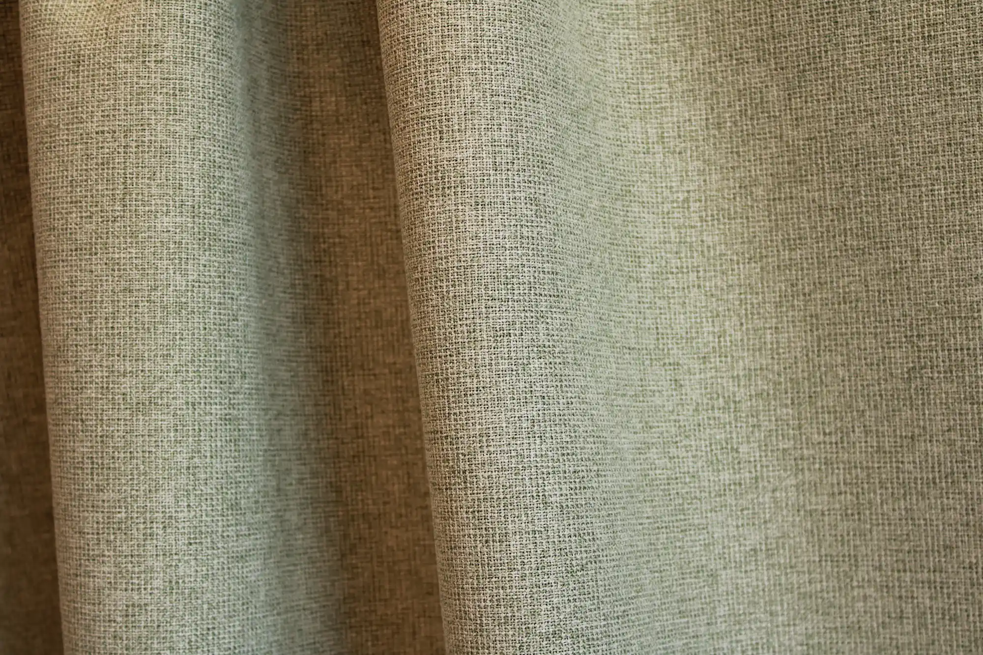Sfeerfoto van groene verduisterende PureShade gordijnen. De groene kleur en de fijne geweven structuur komen duidelijk naar voren.