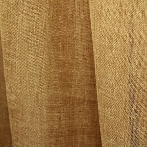 Okergele linnenlook vitrage met een onregelmatige weefstructuur, gefotografeerd in een plooi. De transparante stof laat de structuur en de kleur van dichtbij zien.
