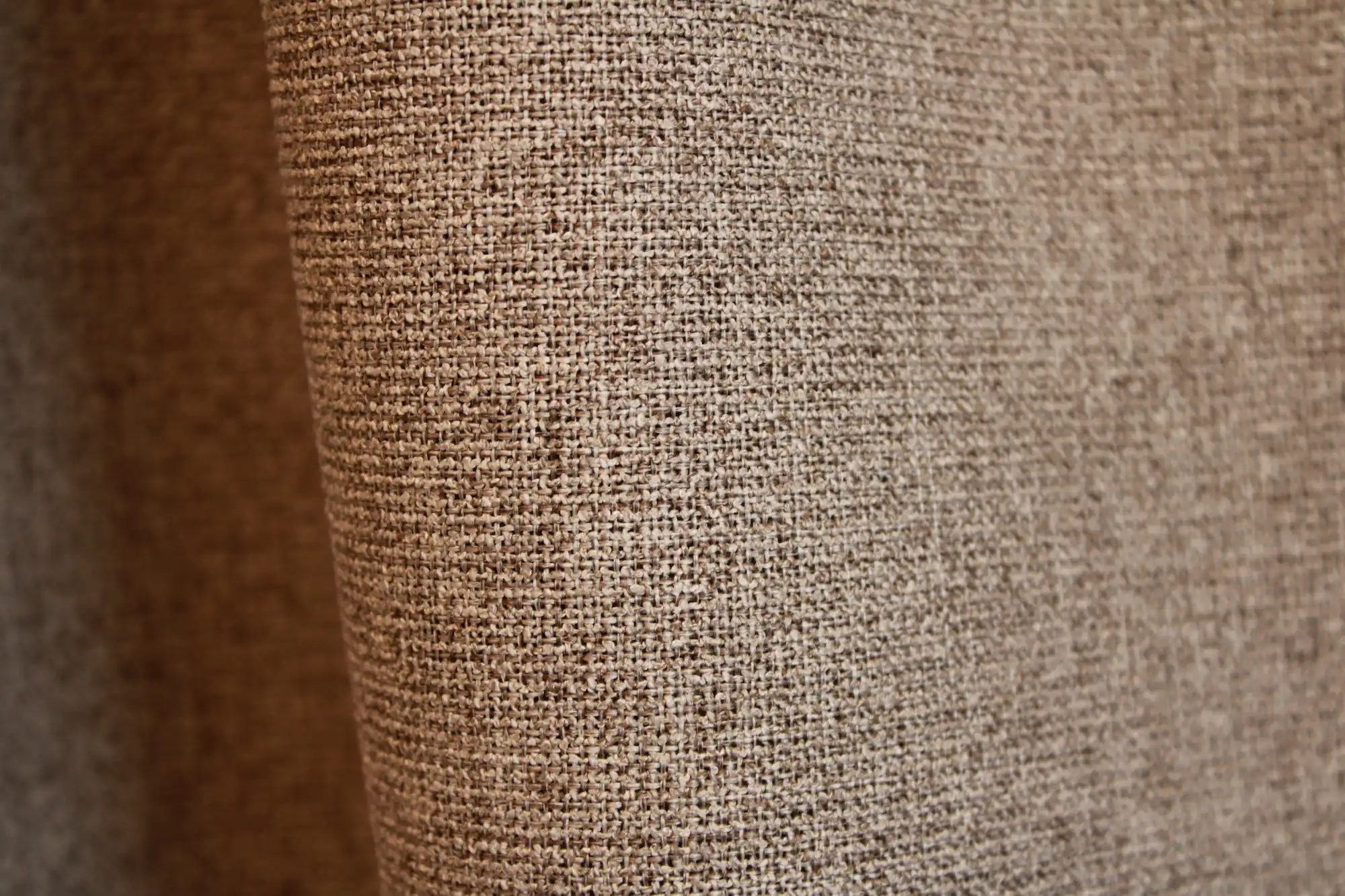 Detail van taupe PureShade gordijnstof. De geweven structuur aan de voorzijde en de verduisterende achterkant in dezelfde taupetint.